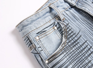 Detail of light blue flared jeans with black abstract graffiti print and metal rivets