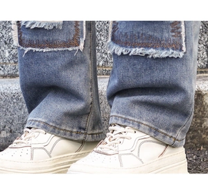 Close-up of distressed denim jeans with fringe details and off-white chunky sneakers