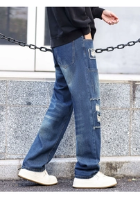 Detail of distressed dark blue jeans featuring cargo side pockets and vintage ripped patches