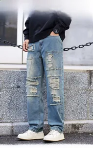 Detail view of distressed light blue denim jeans with heavy ripped patchwork design