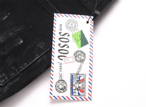 Detailed macro shot of vintage SOSOU tags and washed black denim fabric texture