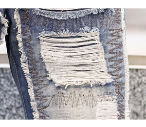 Detail of distressed blue denim with heavy rips and zigzag reinforcement stitching