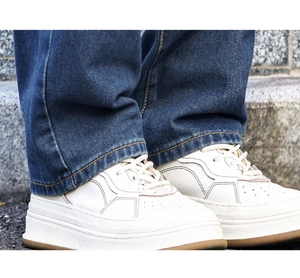 Close-up of white leather platform sneakers with stitched panels and breathable toe box