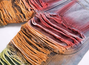 Macro detail of colorful gradient fringe and distressed rips on street style denim jeans