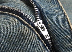 Detail of durable metal zipper closure on vintage blue denim jeans with twill texture