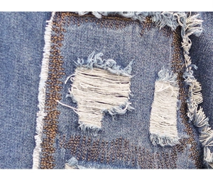 Close-up of distressed denim jeans with frayed holes and contrast stitching detail