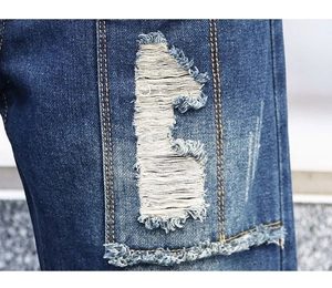 Close-up of vintage distressed denim pants with heavy ripping and frayed edge texture