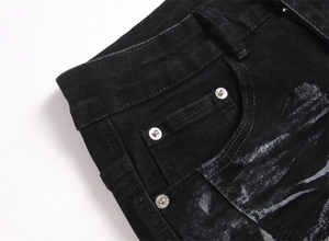 Close-up of black denim fabric with silver rivets and unique artistic white splatter print