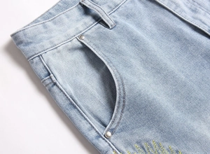 Close-up of light blue denim jeans showing metal rivets and yellow decorative stitching