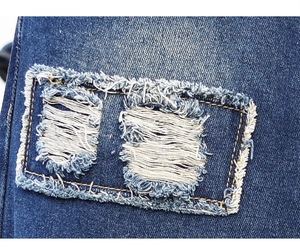 Close-up of distressed denim detail featuring ripped holes and contrast stitching