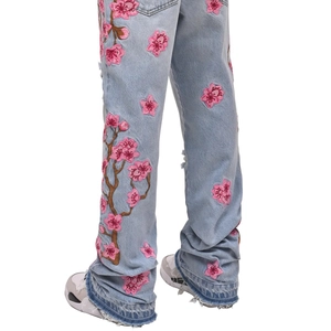Jean évasé bleu pour homme avec broderie cerisier rose et détails d'ourlet effiloché