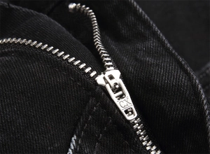 Detailed macro view of silver CX metal zipper on black slim fit denim fabric texture