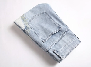 Detail of light blue distressed jeans showing vintage ripped effects and yellow stitching