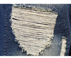 Gros plan détaillé du denim vieilli avec trous déchirés et bords effilochés sur le jean