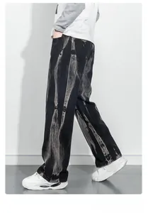 Gros plan sur le denim noir délavé à l'acide avec motif tie-dye vertical sur le pantalon