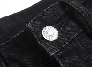 Macro shot of silver metal button with JEANS engraving on black denim trousers