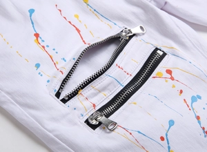 Macro shot of white slim denim pants featuring colorful ink spray and dual metal zippers
