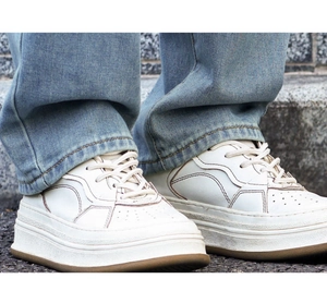 Close-up of retro cream chunky sneakers with brown contrast stitching on asphalt ground