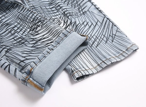 Detailed close-up of light blue denim cuffs featuring black abstract line print and stitching