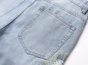 Close-up of light blue washed denim jeans featuring back pocket with zigzag embroidery
