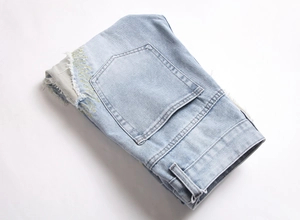 Detailed view of pentagon pocket with frayed edges and yellow star embroidery on blue jeans