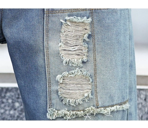 Macro view of distressed denim texture featuring ripped holes and double stitching