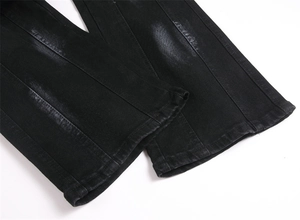 Macro view of men's slim black flared jeans featuring vertical patchwork and faded wash