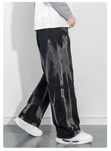 Détail du jean noir ample avec une texture tie-dye blanche unique effet de vagues