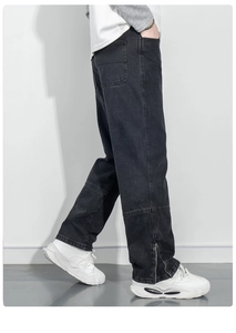 Gros plan d'un jean cargo noir avec fermeture éclair en métal au bas et denim délavé