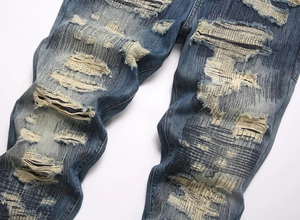 Detailed view of heavy washed denim jeans with distressed patches and raw edges