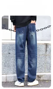 Detail of distressed texture and faded wash on rear pockets of loose fit men's jeans