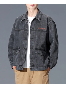 Detail view of washed denim jacket with orange chest embroidery and large flap pockets