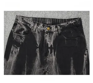 Détail de la taille du jean en denim noir enduit avec bouton métallique et passants