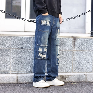 Men's vintage distressed jeans with heavy patchwork and ripped details in deep blue denim