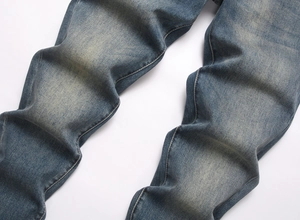 Detail of vintage washed blue denim fabric with yellow mud tint and stitching