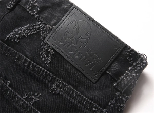 Detail of black washed denim waist featuring embossed skull leather patch and distress texture