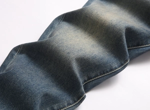 Close-up of vintage blue wash denim jeans with faded texture and twill fabric detail