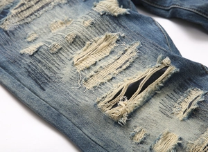 Detail of vintage punk ripped jeans showing distressed patches and denim texture