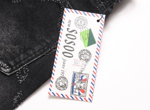 Detail of SOSOO black distressed denim jeans with faded textures and branded hangtag