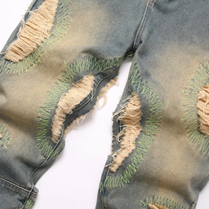 Men's vintage distressed blue jeans with neon green stitching and ripped fringe details