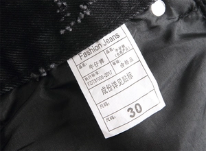 Macro detail of washing label and size tag on black punk straight leg denim jeans