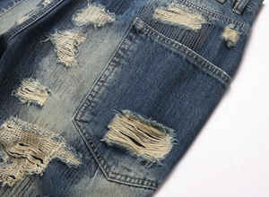 Detail of vintage blue denim jeans showing heavy distressed ripped holes and worn texture