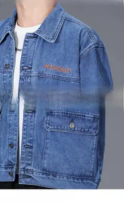 Detailed view of blue denim jacket shoulder and pocket with orange waveakear embroidery