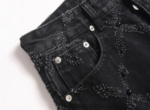 Detail showing distressed black denim with cross pattern and silver metal rivets