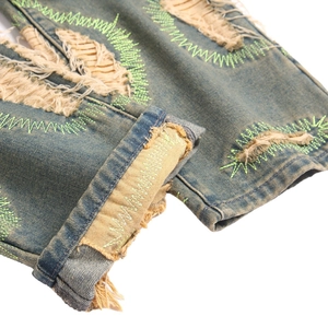 Distressed mid-rise straight jeans with neon green stitching and ripped denim details