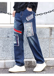 Close-up of distressed denim patch detail with red ribbon and Lover embroidery on wide leg jeans