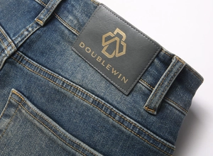 Detailed close-up of dark blue washed denim with a branded leather patch and gold stitching