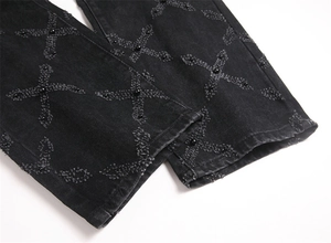 Detail of black washed denim with cross embroidery and polished black bead accents