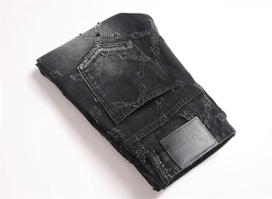 Detail of cross embroidery and bead accents on black loose fit high-street jeans