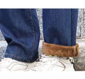 Detail of dark blue denim jeans with thick brown fleece lining and folded cuff design